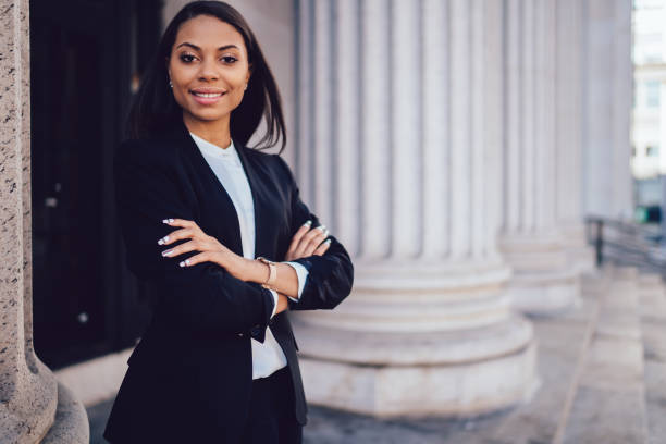 Half length portrait of successful happy businesswoman with dark skin crossed arms smiling at camera.Prosperous African American financial manager dressed in formal wear standing near copy space stock photo