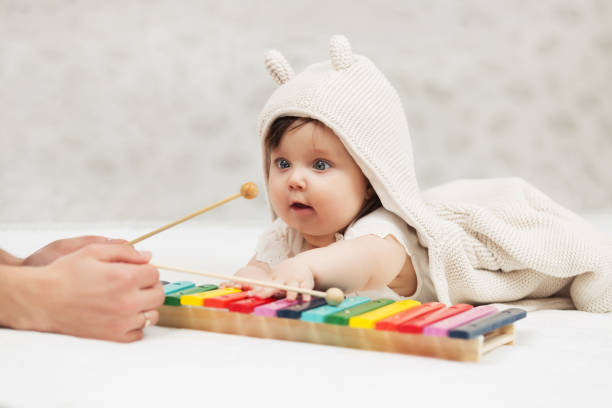 Half year baby girl playing with xylophone toy on blanket stock photo
