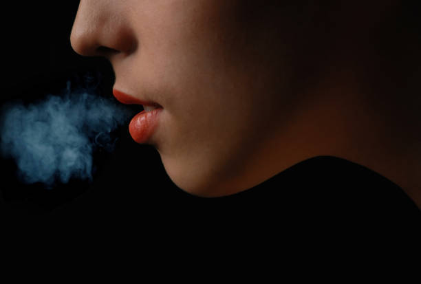 Half-face of the smoking woman against black background stock photo