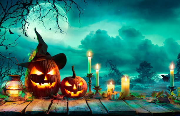halloween bei nacht - kürbisse mit hexenhut und kerzen auf dem tisch in mystery landschaft - romolotavani stock-fotos und bilder