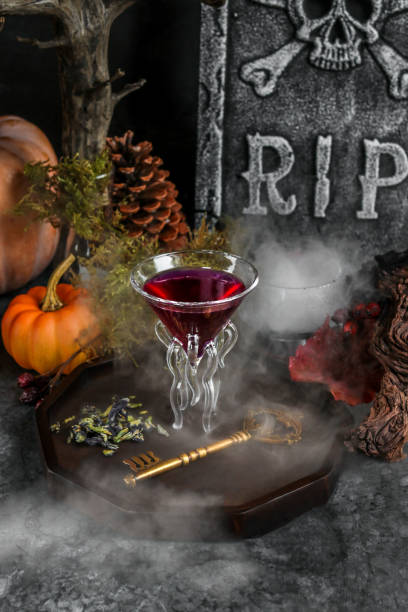 Halloween cocktail in purple with spooky fog and pumpkins stock photo