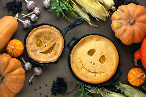 Halloween party home baked pumpkin pies Halloween kids party pumpkin pies baking concept, top down view on a cute couple of skillet baked pumpkin pies with smiling alike Jack-o-lantern faces tart dessert stock pictures, royalty-free photos & images