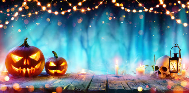 Halloween Party - Jack O' Lanterns And String Lights On Table In Misty Forest Pumpkins And Skull On Table At Dust In Forest halloween background stock pictures, royalty-free photos & images