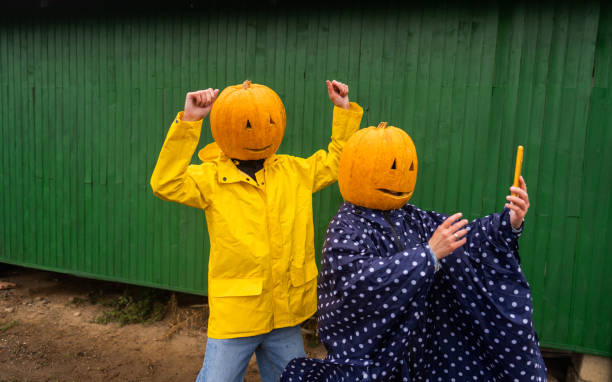 Halloween selfie Photo of a couple with pumpkins on the heads, making a selfie. smart phone green background stock pictures, royalty-free photos & images