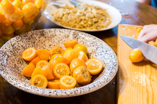Halved Fresh Kumquats on Kitchen Table Halved Fresh Kumquats on Kitchen Table kumquat stock pictures, royalty-free photos & images