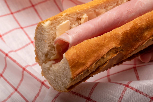 ham sandwich with a French baguette and tea towel in the background stock photo