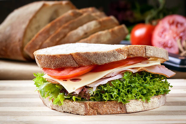 Ham Sandwich with Salad and Cheese Ham sandwich with salad and cheese.  Loaf of bread behind. swiss culture stock pictures, royalty-free photos & images