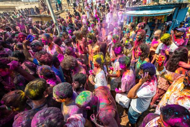 10.03.2020 Hampi. India. Crowd of people throw loose color paint at each other before the start of lockdown and covid 19 pandemic. Festival of love, triumph of good over evil and arrival of spring 10.03.2020 Hampi. India. Crowd of people throw loose color paint at each other before the start of lockdown and covid 19 pandemic. Festival of love, triumph of good over evil and arrival of spring hampi stock pictures, royalty-free photos & images