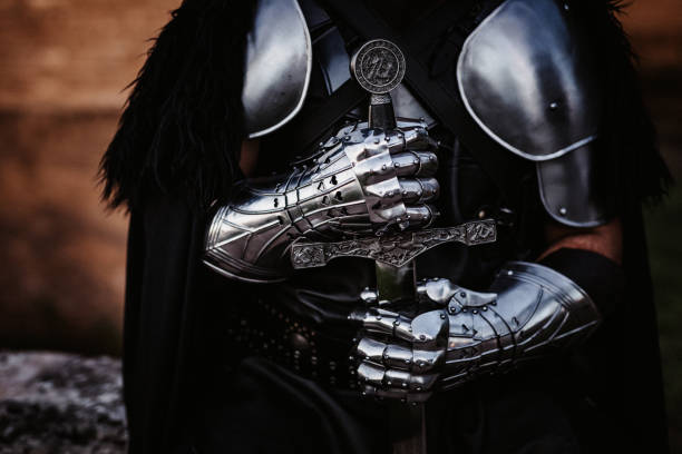Hand and sword of a medieval fantasy knight Hand and sword of a medieval fantasy knight,creative dramatic color retouching with grain (theater requisites- swords are Chinese mass product) part of an E+ and S+ serie armored clothing stock pictures, royalty-free photos & images