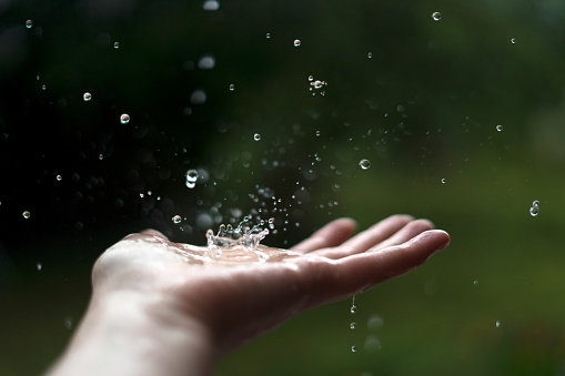 Hand of woman catching raindrops.