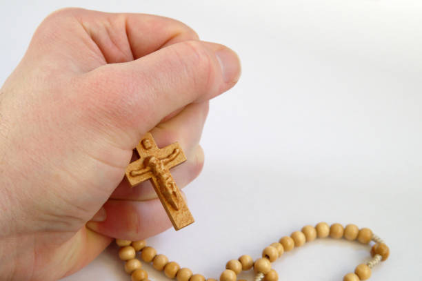 Hand cradling Christian Rosary Chaplet on White background stock photo