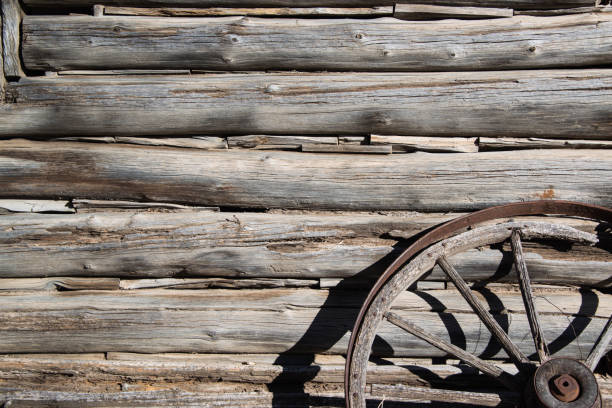 Hand cut logs from historic old cabin and wagon wheel stock photo