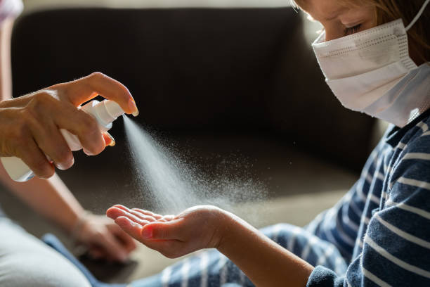 Hand disinfection is the most important thing during corona virus! Unrecognizable single parent spraying hand sanitizer to her little boy's hand. Boy is with face mask. spraying stock pictures, royalty-free photos & images