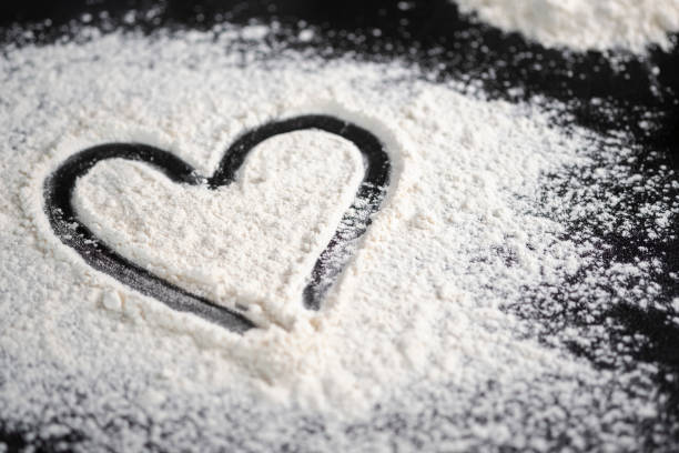 Hand drawn heart on table sprinkled with confectionery flour stock photo