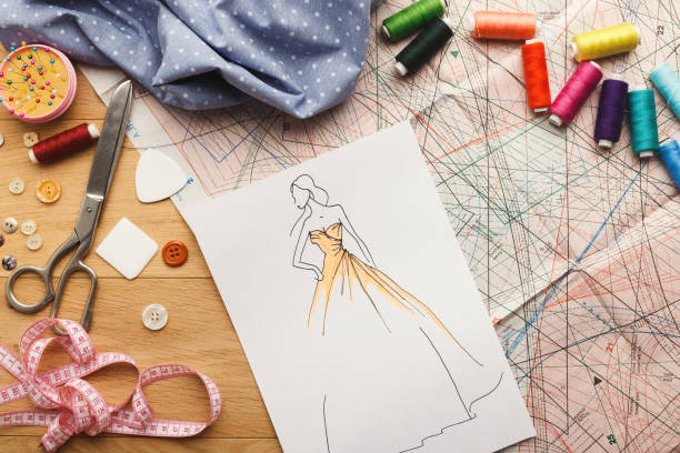 Hand drawn sketches for new fashion collection Dressmaking and fashion collection background. Drawn sketches, sewing patterns and various designer accessories on messy table, top view. Creativity concept fashion dress sketches stock pictures, royalty-free photos & images