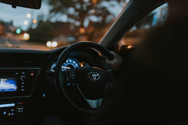 Hand driving Toyota Auris car dashboard with right-hand position at evening stock photo