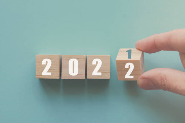 Hand flipping over wooden block of 2021 to 2022, New Year Resolutions, business concept stock photo