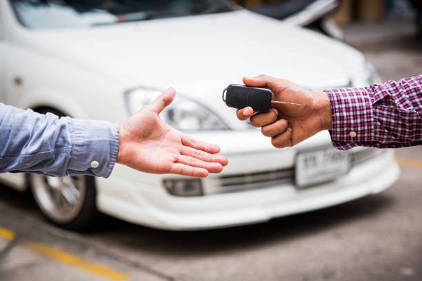 Hand giving car key on car background stock photo
