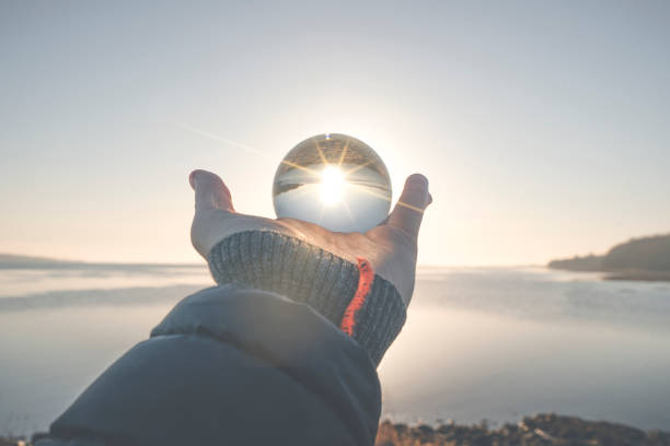 Hand holding a crystal ball in the winter sunrise stock photo