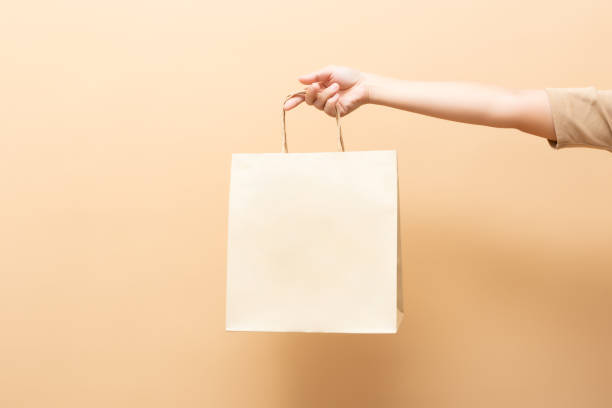 背景に隔離された紙袋を手で握る - 買い物袋 ストックフォトと画像