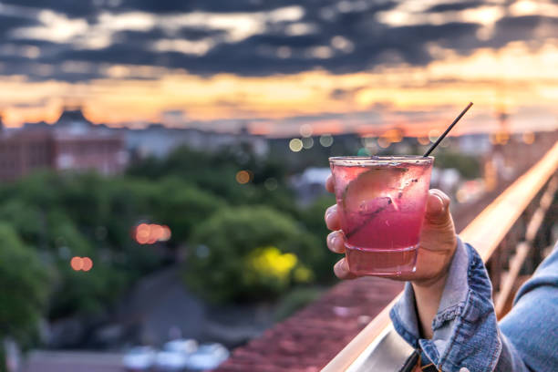 A hand holding a pink alcoholic beverage at a Savannah, Georgia at sunset stock photo
