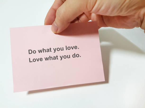Hand holding a sticky pad showing the words "Do what you love. Love what you do." stock photo