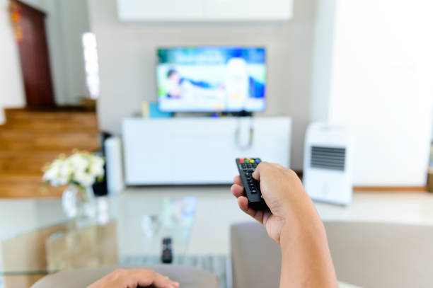 Hand holding audio and tv remote control. Rest at home. stock photo