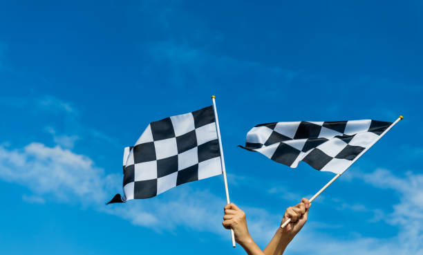 Hand holding checkered race flag in the air stock photo