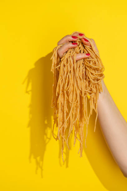 Hand holding cooked spagetti pasta stock photo