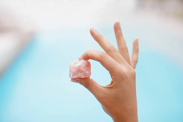 Hand holding crystal at poolside  rose quartz stock pictures, royalty-free photos & images