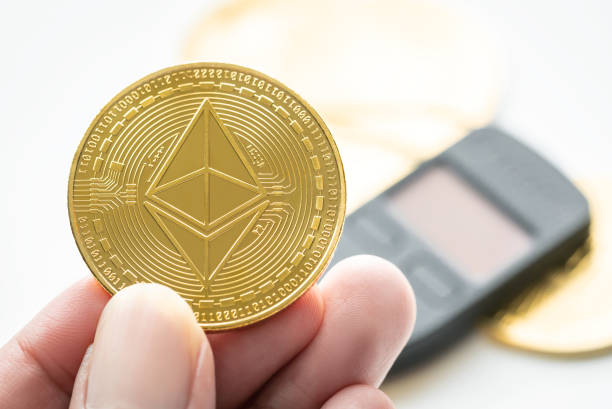 Hand holding ETH ethereum gold coin with hardware wallet in background. Hand holding ETH ethereum gold coin with hardware wallet in background.  With Ethereum  stock pictures, royalty-free photos & images
