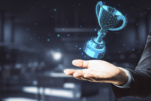 Hand holding glowing polygonal winner cup stock photo