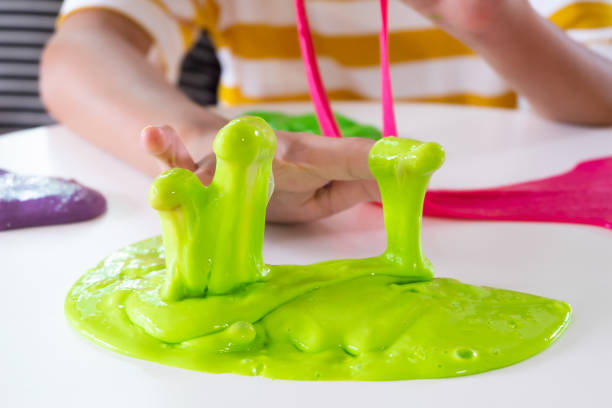 Hand Holding Homemade Toy Called Slime, Sibling boy and girl having fun and being creative by science experiment. stock photo