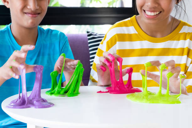 Hand Holding Homemade Toy Called Slime, Sibling boy and girl having fun and being creative by science experiment. stock photo