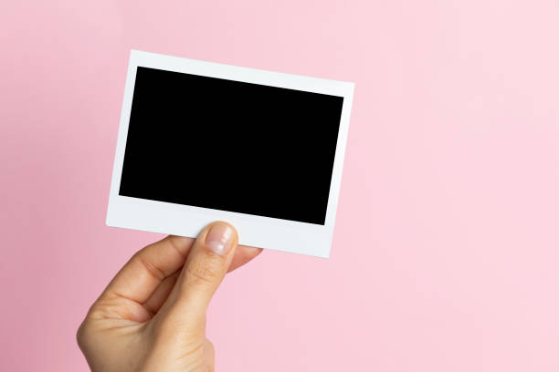 Hand Holding Instant Photo Hand holding instant photo, pink background. hand photos stock pictures, royalty-free photos & images