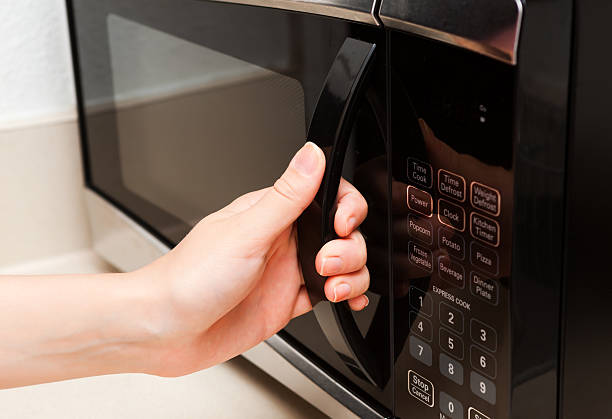 Hand holding microwave door close up stock photo