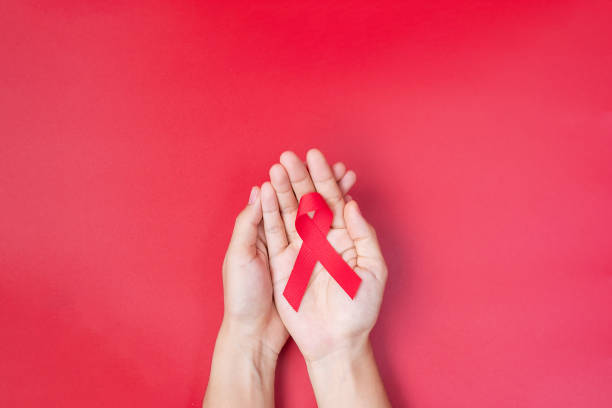 mão segurando red ribbon para apoiar pessoas vivendo e doenças. saúde e conceito de sexo seguro. dia mundial da aids de dezembro e mês de conscientização sobre o câncer de mieloma múltiplo - aids - fotografias e filmes do acervo