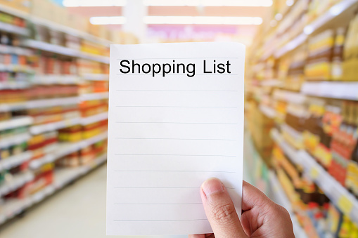 Foto de Hand Holding Shopping List Over Supermarket Blur Background e mais fotos de stock de Adulto - iStock