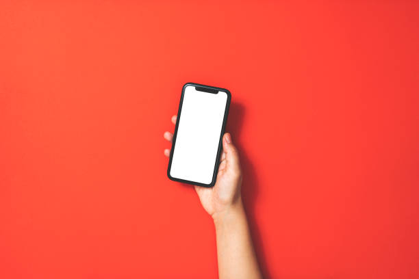 hand holding smart phone on red background - segurar imagens e fotografias de stock