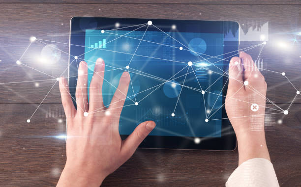 Hand holding tablet with linked graphs and charts concept stock photo