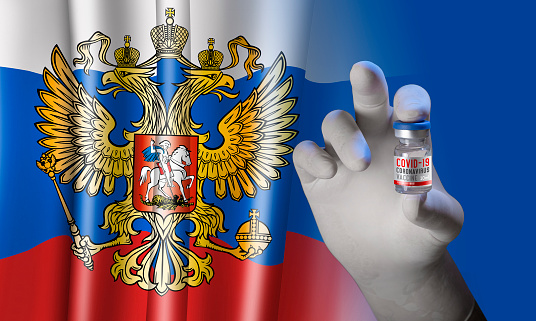 Hand holding vial ampoule vaccine for Corona Virus Covid-19 with russian Flag