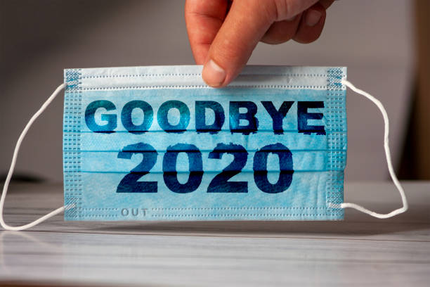 hand holds a medical and protective mask with the word GOODBYE 2020. Concept of coronavirus quarantine. Prevent or stop the spread of the COVID-19 worldwide. The hand holds a medical and protective mask with the word GOODBYE 2020. Concept of coronavirus quarantine. Prevent or stop the spread of the COVID-19 worldwide. 2020 stock pictures, royalty-free photos & images