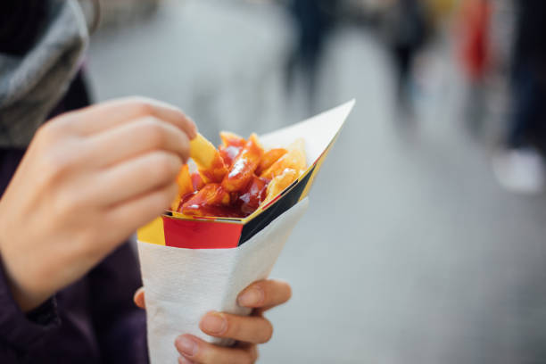 Hand holds a paper cone with french fries in Brussels
