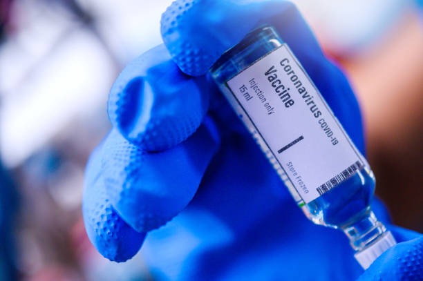 hand houdt coronavirus covid-19 vaccin glazen fles - vaccinatie stockfoto's en -beelden