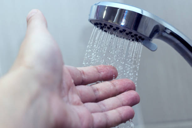 hand in the shower test water temperature stock photo