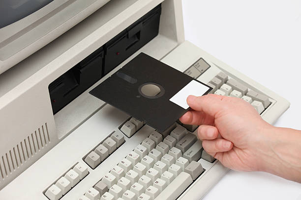 Hand inserting old floppy disk drive into vintage eigthies computer stock photo