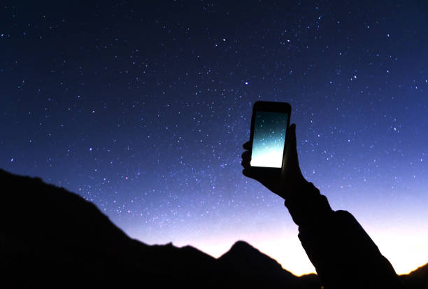 A hand is holding smartphone with starry sky photo: a man is taking a photo starry sky at night. Milky way and galaxy on dark sky. Wifi mobile internet concept A hand is holding smartphone with starry sky photo: a man is taking a photo starry sky at night. Milky way and galaxy on dark sky. Wifi mobile internet concept astronomy photos stock pictures, royalty-free photos & images