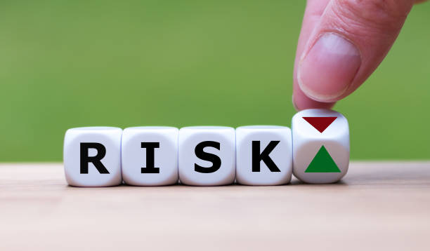 Hand is turning a dice and changes the direction of an arrow symbolizing that the risk is going up (or vice versa) stock photo