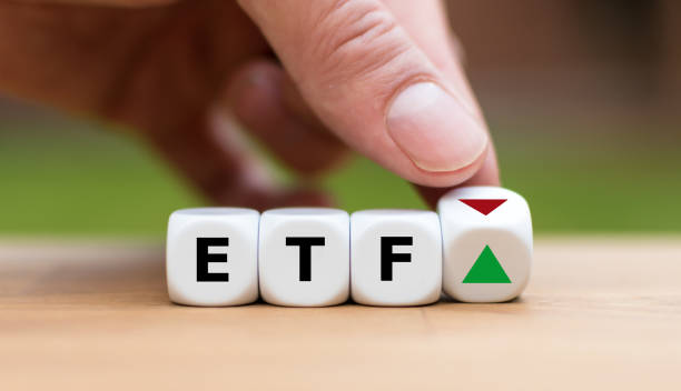 Hand is turning a dice and changes the direction of an arrow symbolizing that the value of an ETF (Exchange Traded Fund) is going up (or vice versa) stock photo