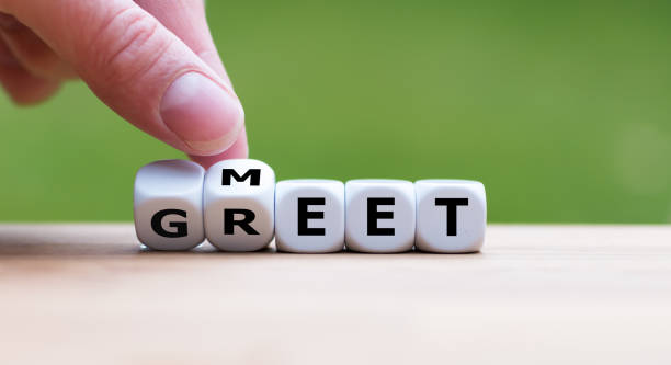 Hand is turning a dice and changes the word "Meet" to "Greet" stock photo